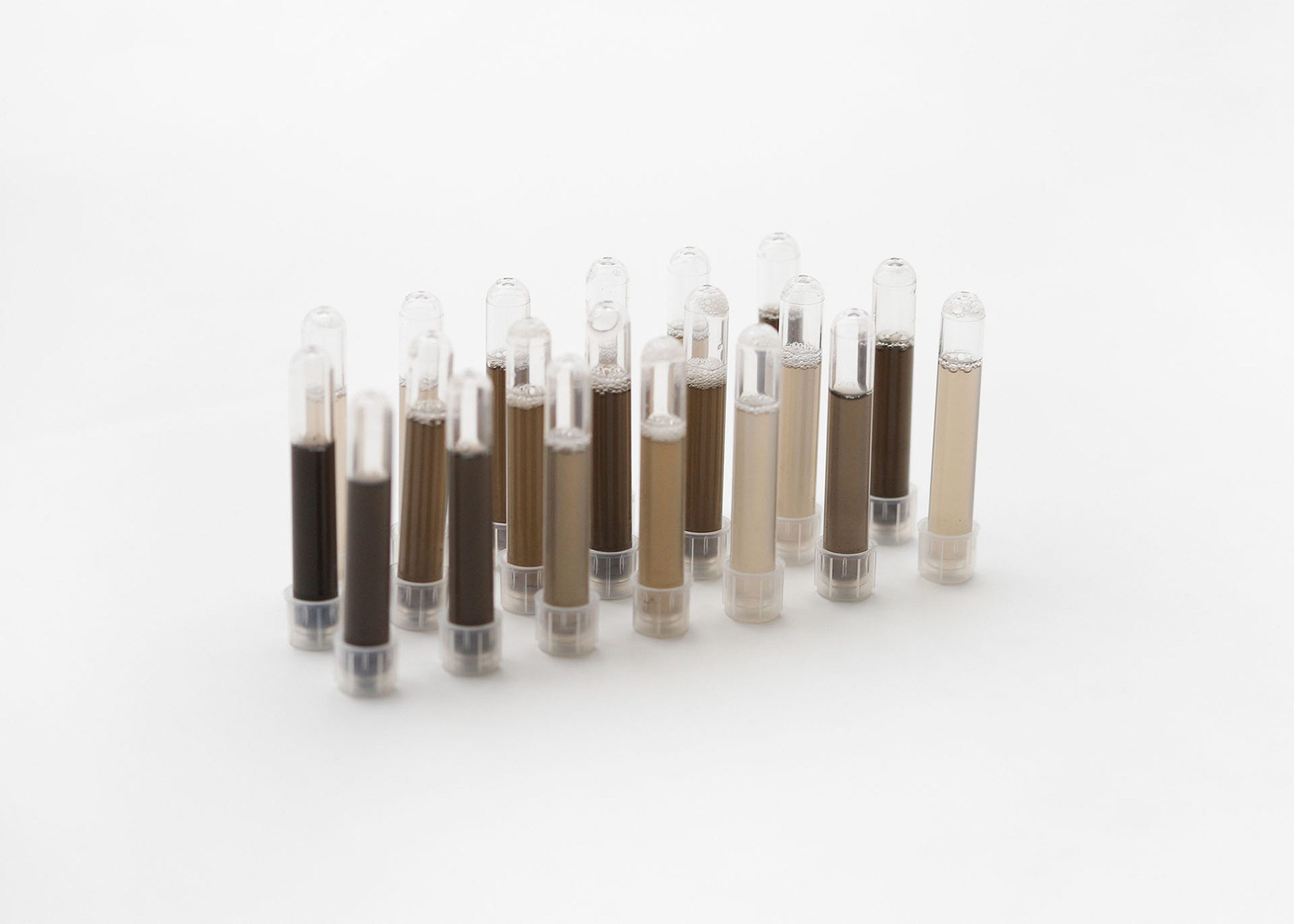 Photo of a tray of test tubes containing skin-coloured liquids from light beige to dark brown